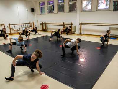 E ci conduce infine nella sala prove, occupata da un gruppo di ragazze in tuta che si muove al ritmo di una canzone pop